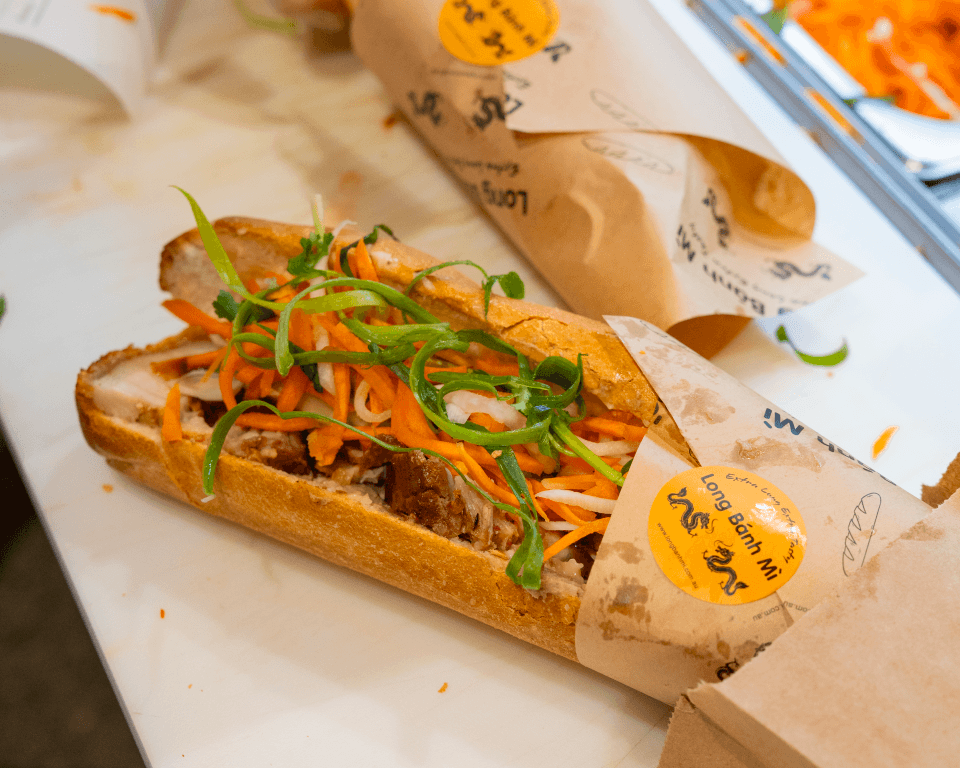 Crackling roasted pork belly bánh mì, sliced open showing pork, pickled carrot, cucumber and coriander